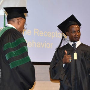 Student giving a thumbs up as he receives his diploma