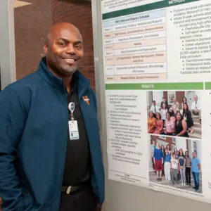 A man stands with a poster smiling