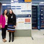 Two people stand in front of a poster