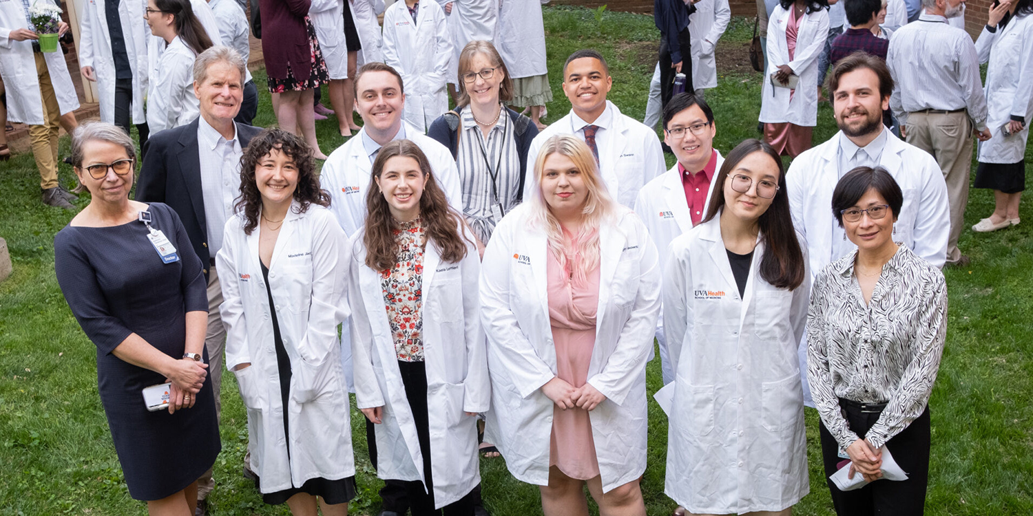 PhD students standing with faculty mentors at lab coat ceremony.
