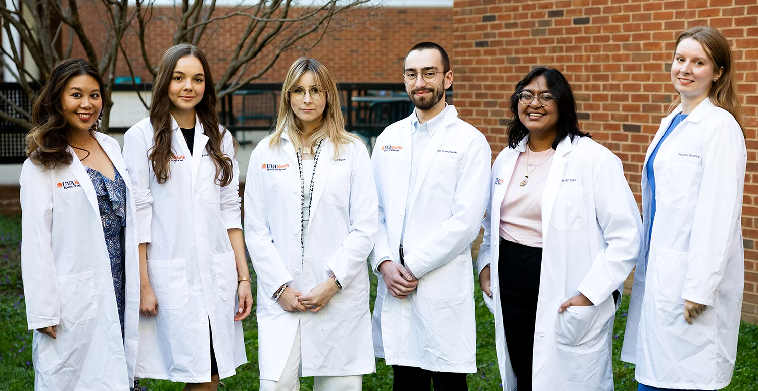 research students in white lab coats standing in courtyard