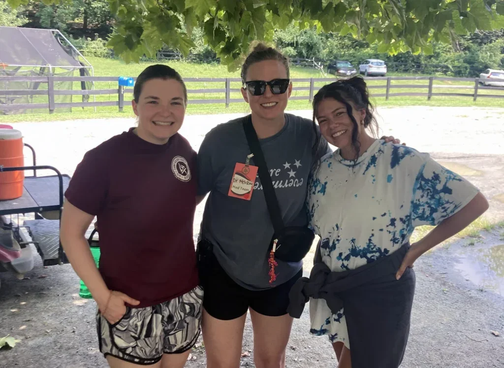 three medical professionals standing together for a group photo at a children's camp