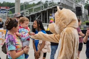 Rufus the Bear shaking hands with a baby