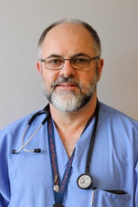 portrait of Dr. Brady in blue scrubs in front of a plain wall