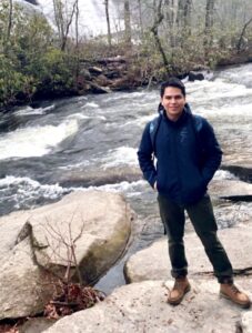 Gustavo standing by a river on a winter day