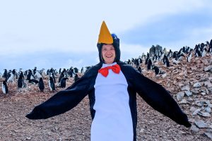 Daniel dressed in a penguin costume among penquins