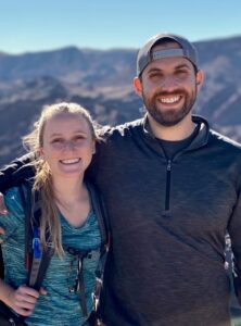 John Sweeney and partner smiling in front of mountains