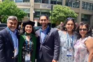 Meg Keswani standing in graduation regalia with her family