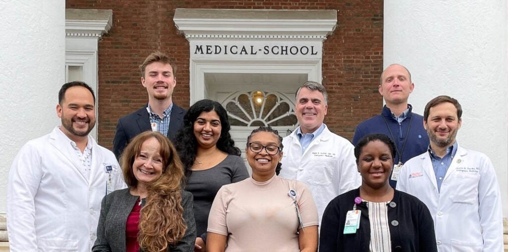 group photo of the research team standing outside on the Old Medical School steps