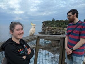 Sigal smiling with her husband and a parrot on overlooking a bluff
