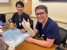 two residents practice making casts for broken bones