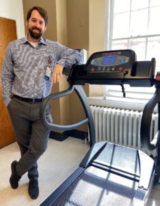 Dr. Dalrymple standing next to treadmill in the exercise physiology core lab