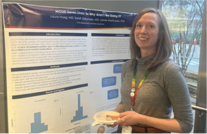 Dr. Laura Hoeg stands, smiling, with her poster on factors limiting presecription of medications for opioid use disorders by Internal Medicine and Family Medicine residents and faculty.