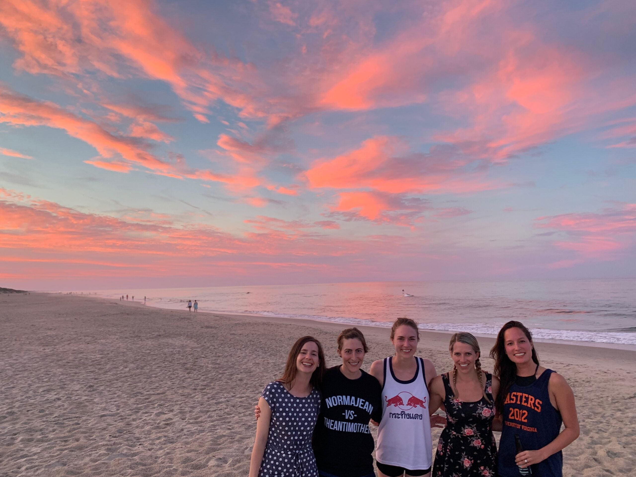 a group of students hanging out at the beach during sunset