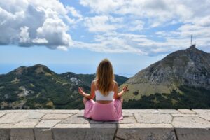 Woman meditating with beautiful mountains in background.
