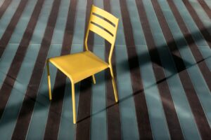 Wooden chair on striped carpet.