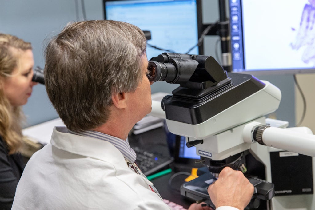 Faculty and resident view slides in a microscope.