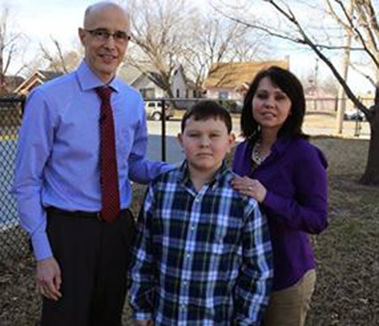 Dr. Jim Tucker stands with a young subject and his mother