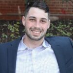 UVA Pharmacology Grad Student smiles while wearing a suit and a white shirt