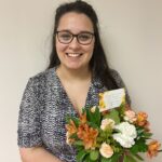 Jessica Hatter smiles while holding flowers after her dissertation defense
