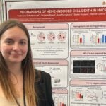 Kasia smiles and stands in front of her science poster