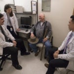 three doctors talking to a patient