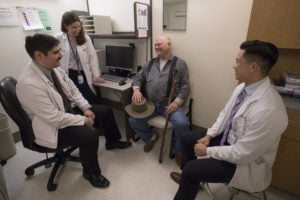 three doctors talking to a patient