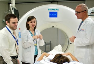 Photo: Faculty working with Residents at a CT Scanner.