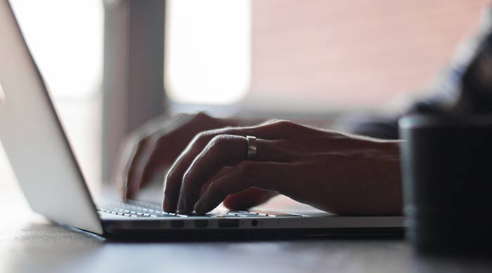 A closeup of hands typing on a laptop