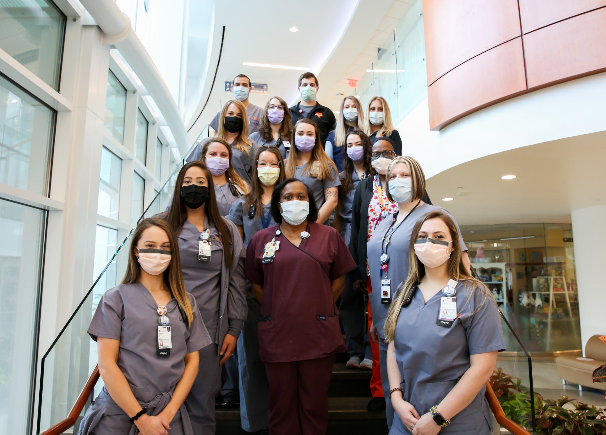 UVA Radiology Diagnostic technologists pose on the stairs in the UVA Health lobby