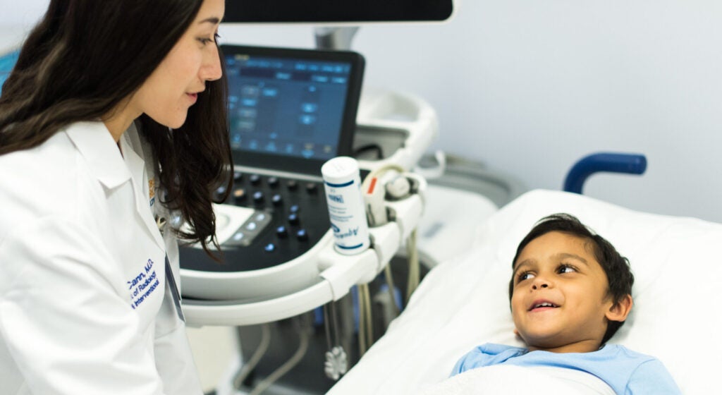 UVA Pediatric Radiologist speaks with a young patient on an exam table