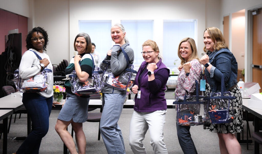 Clinical Research Coordinators Leslie Gladney, Abby Lyons, Brigitte Kelly, Caroline Flournoy, Kathy Repich, Katie Landes pose with UVA merchandise