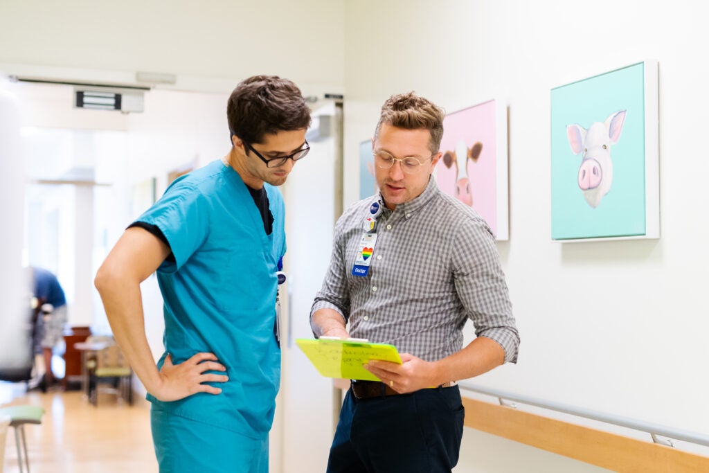 Faculty member and trainee look at clipboard in pediatric radiology hallway