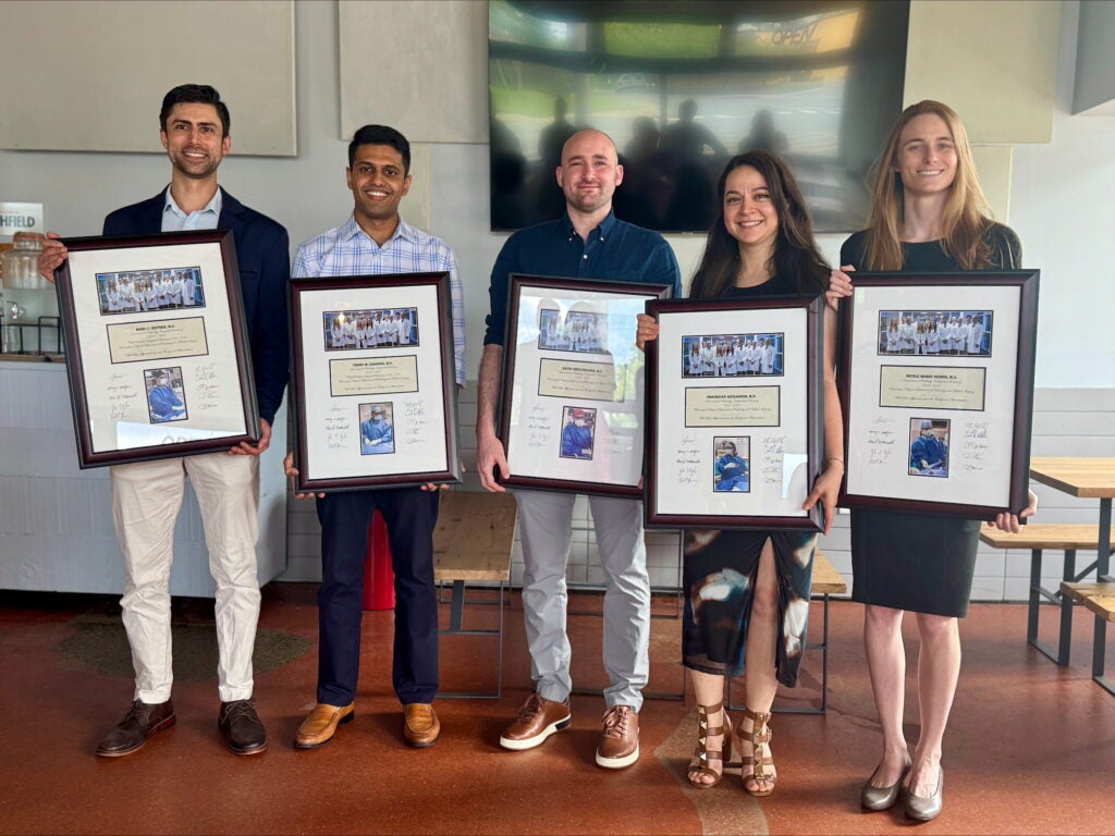 Five graduation IR residents stand with framed plaques