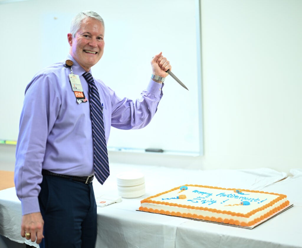 James Carnes poses, about to cut into cake with force