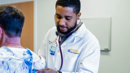 A University of Virginia male resident doctor listens to a patient's lungs.