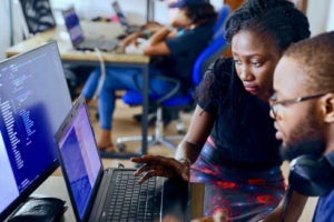 woman showing man how to fix code on his computer
