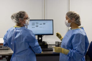 lab members in scrubs talking in front of a computer